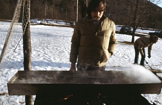 Chuck stands at a steaming pan of maple sap